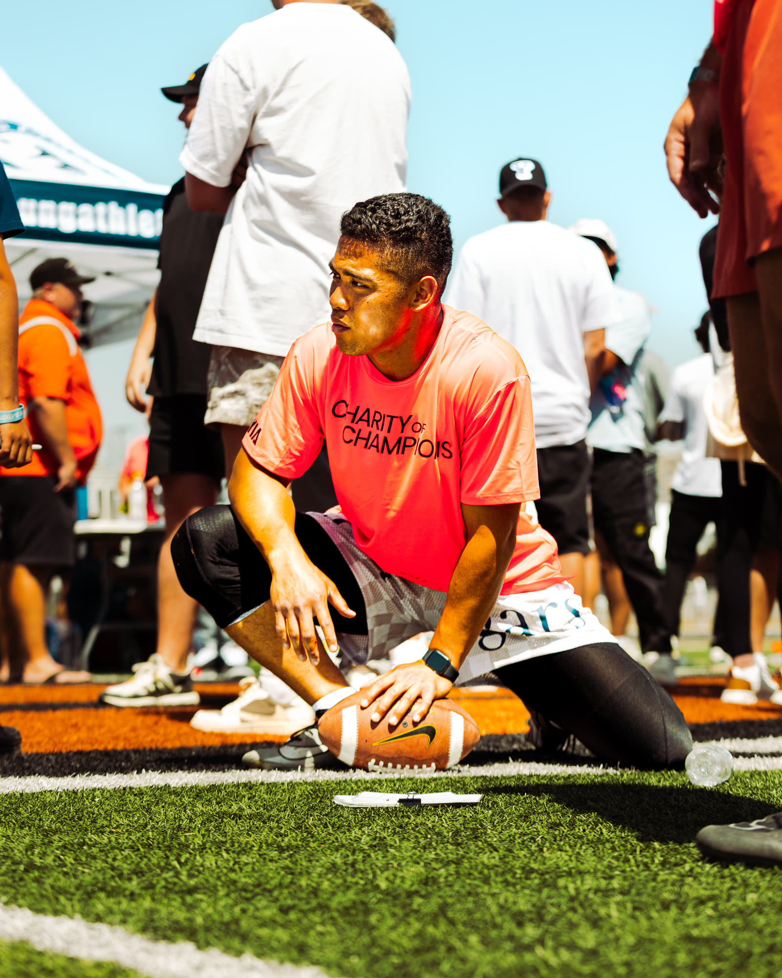 Player crouched with football in Charity of Champions shirt